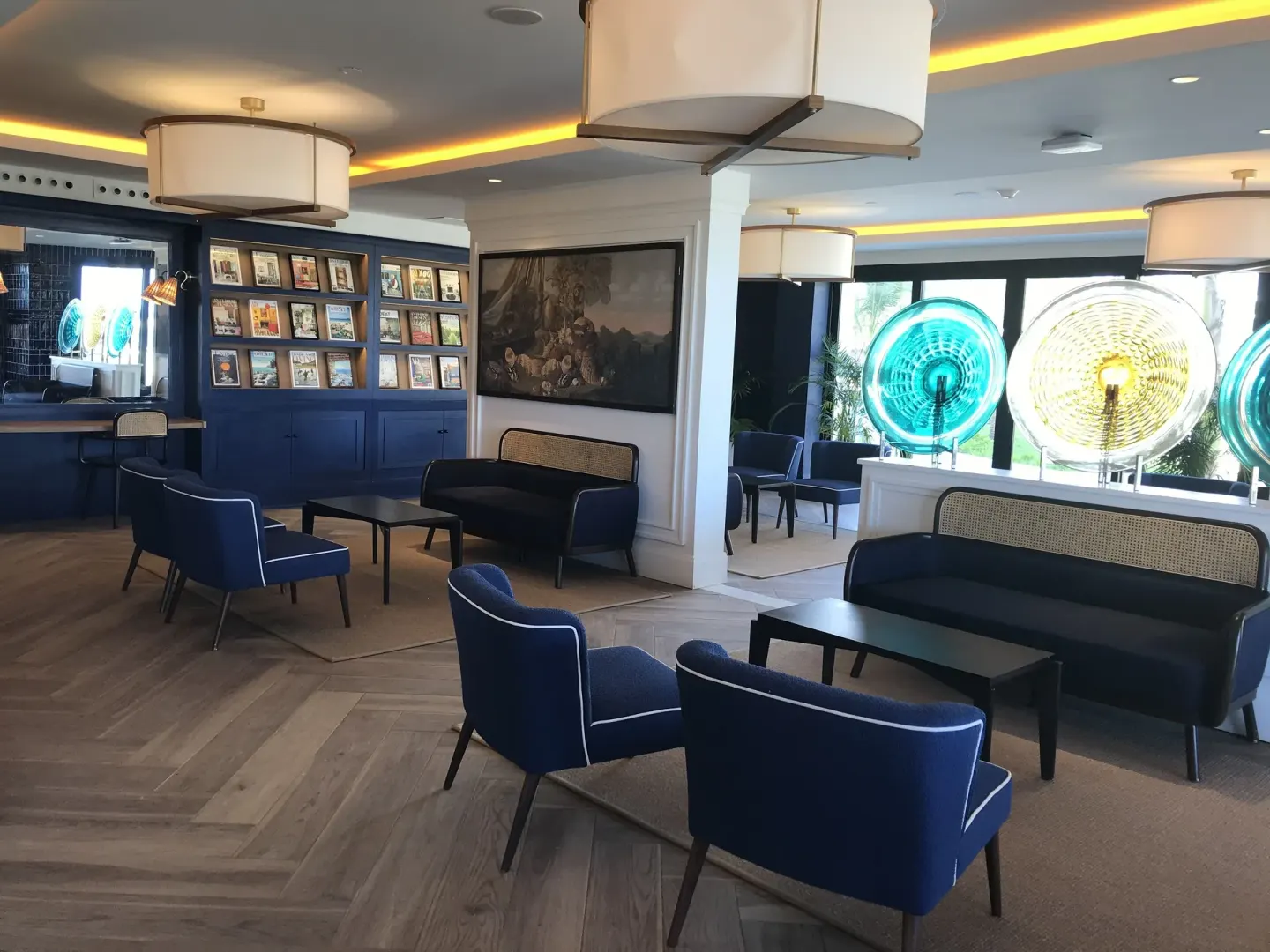 Blue lounge seating, wall art, and colorful glass lamps in a resort lounge at Ocean Coral Spring.