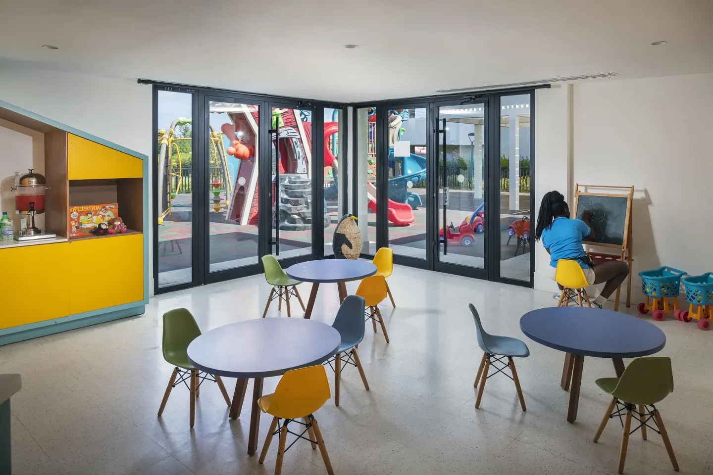 Children's activity room with small tables and a chalkboard at Ocean Coral Spring.