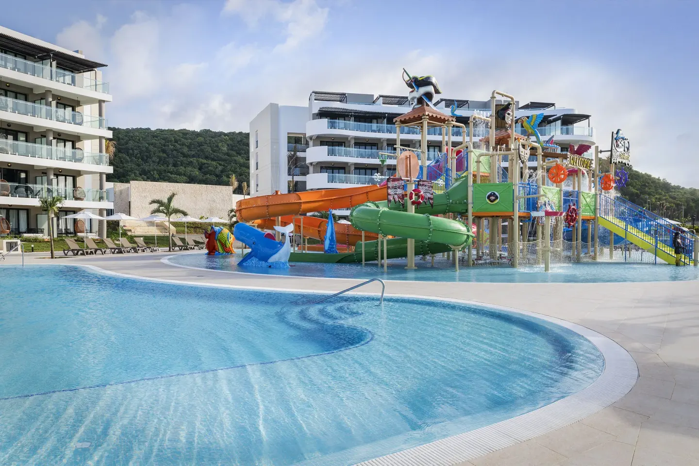 Family pool with colorful water slides beside guest buildings at Ocean Coral Spring.