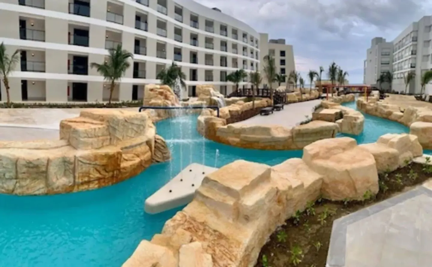 Lazy river with rock waterfalls between hotel buildings at Ocean Coral Spring.
