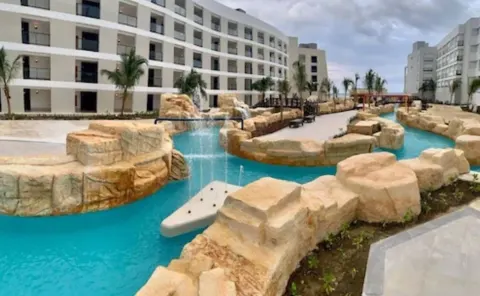 Lazy river with rock waterfalls between hotel buildings at Ocean Coral Spring.