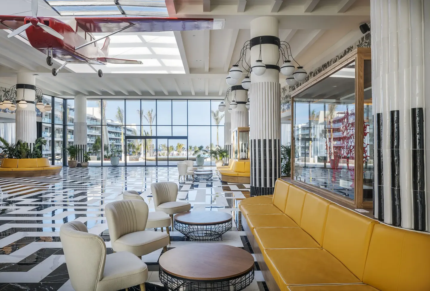 Spacious lobby with yellow seating, glossy floors, and a hanging model plane at Ocean Coral Spring.