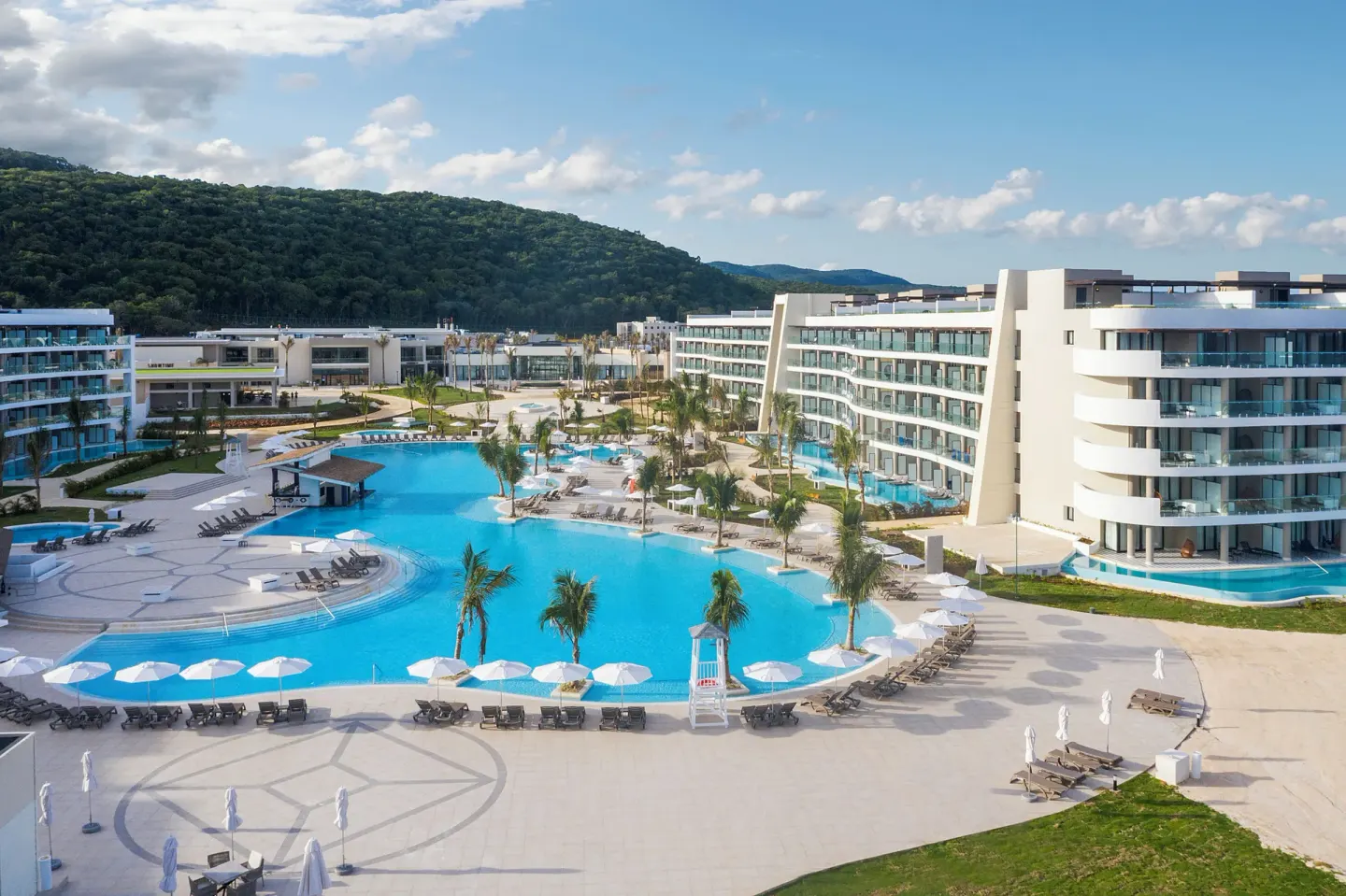 Large pool courtyard with resort buildings and loungers at Ocean Coral Spring.