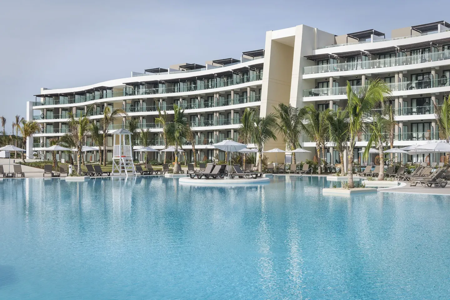 Pool with loungers, palms, and guest room balconies at Ocean Coral Spring.