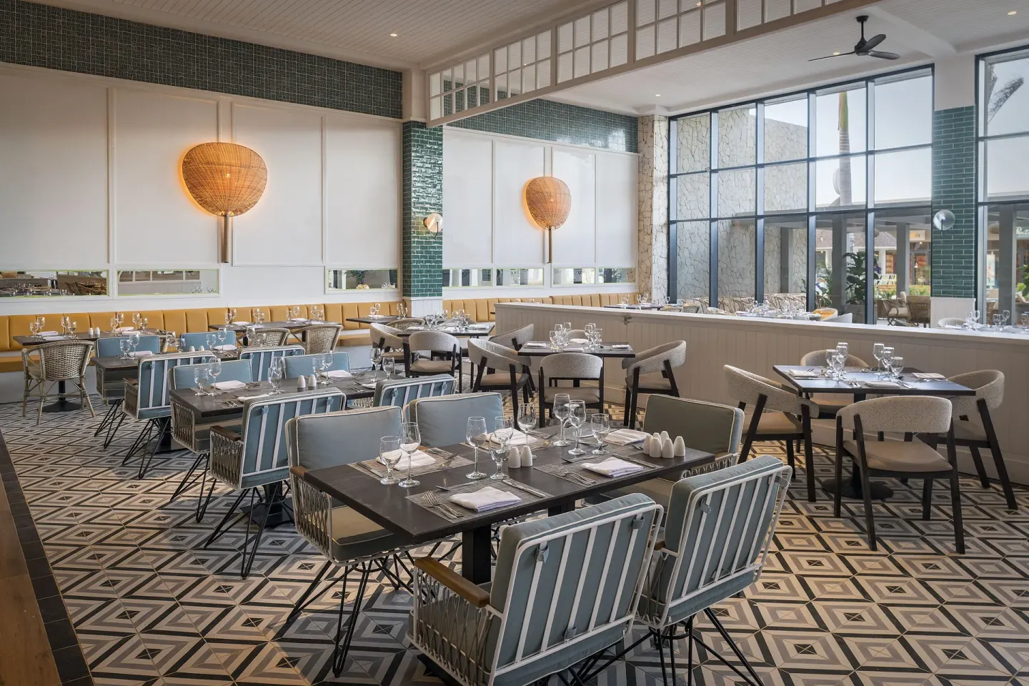 Bright restaurant dining room with set tables and patterned tile at Ocean Coral Spring.