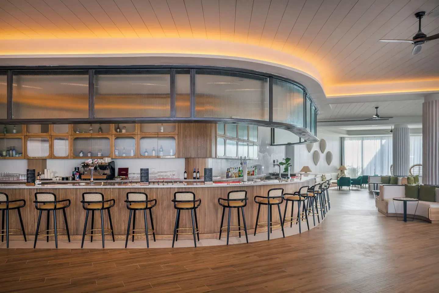 Curved bar with tall stools and lounge seating beyond at Ocean Coral Spring.