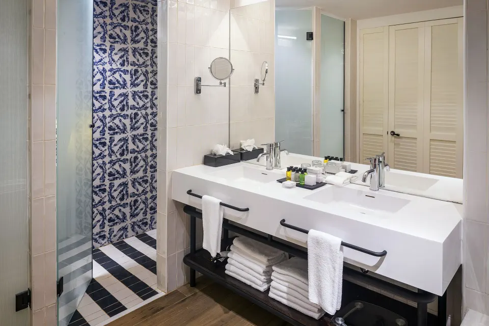 Junior Suite Nature View bathroom at Ocean Coral Spring with double vanity, mirror, and walk-in shower.