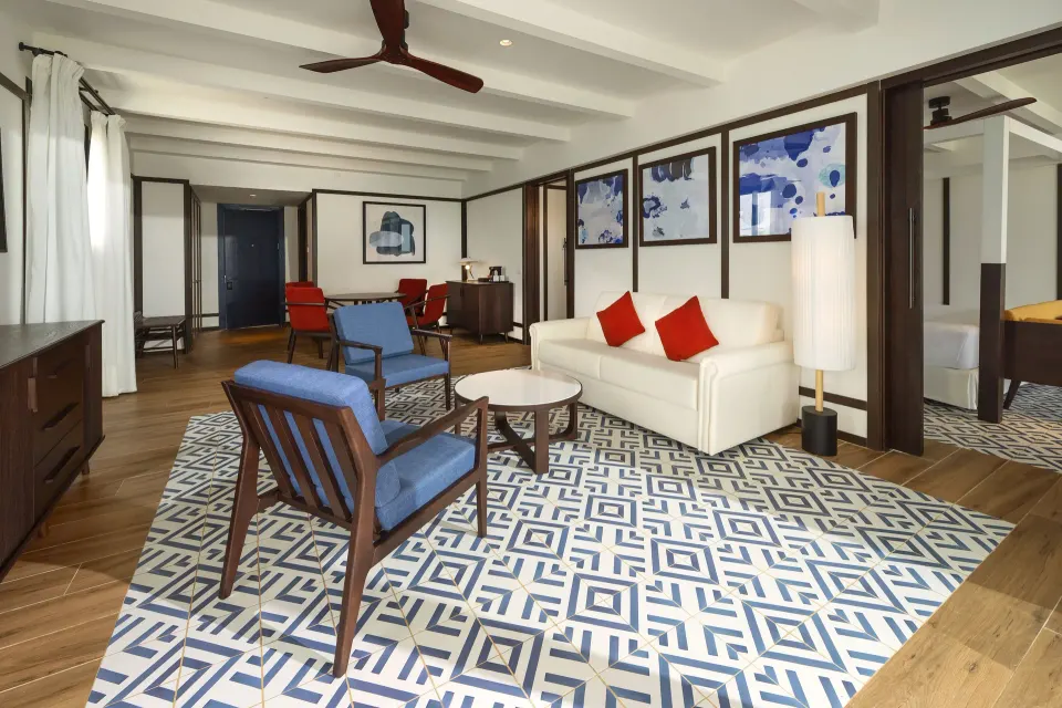 Privilege Master Suite lounge with sofa, blue chairs, and bedroom doorway at Ocean Coral Spring.