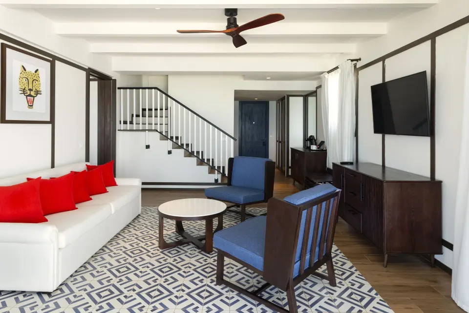 Privilege Master Suite lounge with staircase, sofa, chairs, and TV at Ocean Coral Spring.