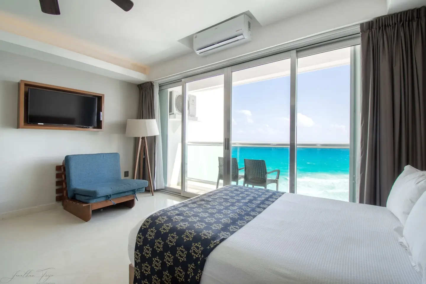 Guest room bed beside sliding balcony doors with ocean view at Ocean Dream Cancun.