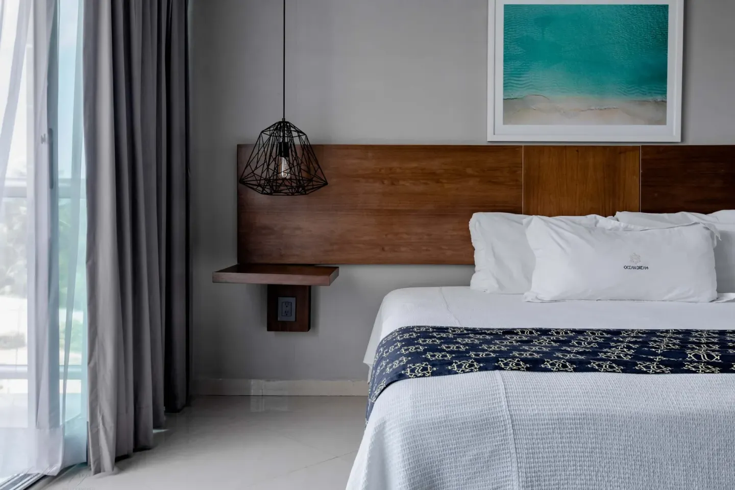 Close view of a king bed beside balcony curtains at Ocean Dream Cancun.