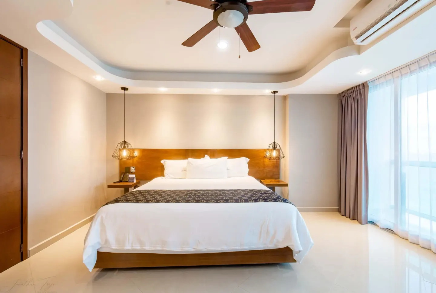King-bed guest room with pendant lights and balcony curtains at Ocean Dream Cancun.