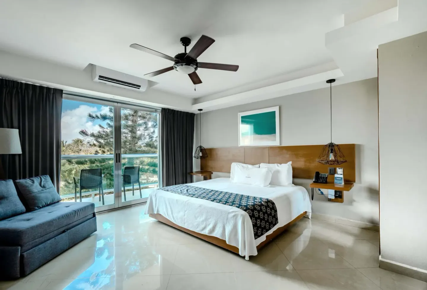 King bed guest room with sofa and balcony doors at Ocean Dream Cancun.