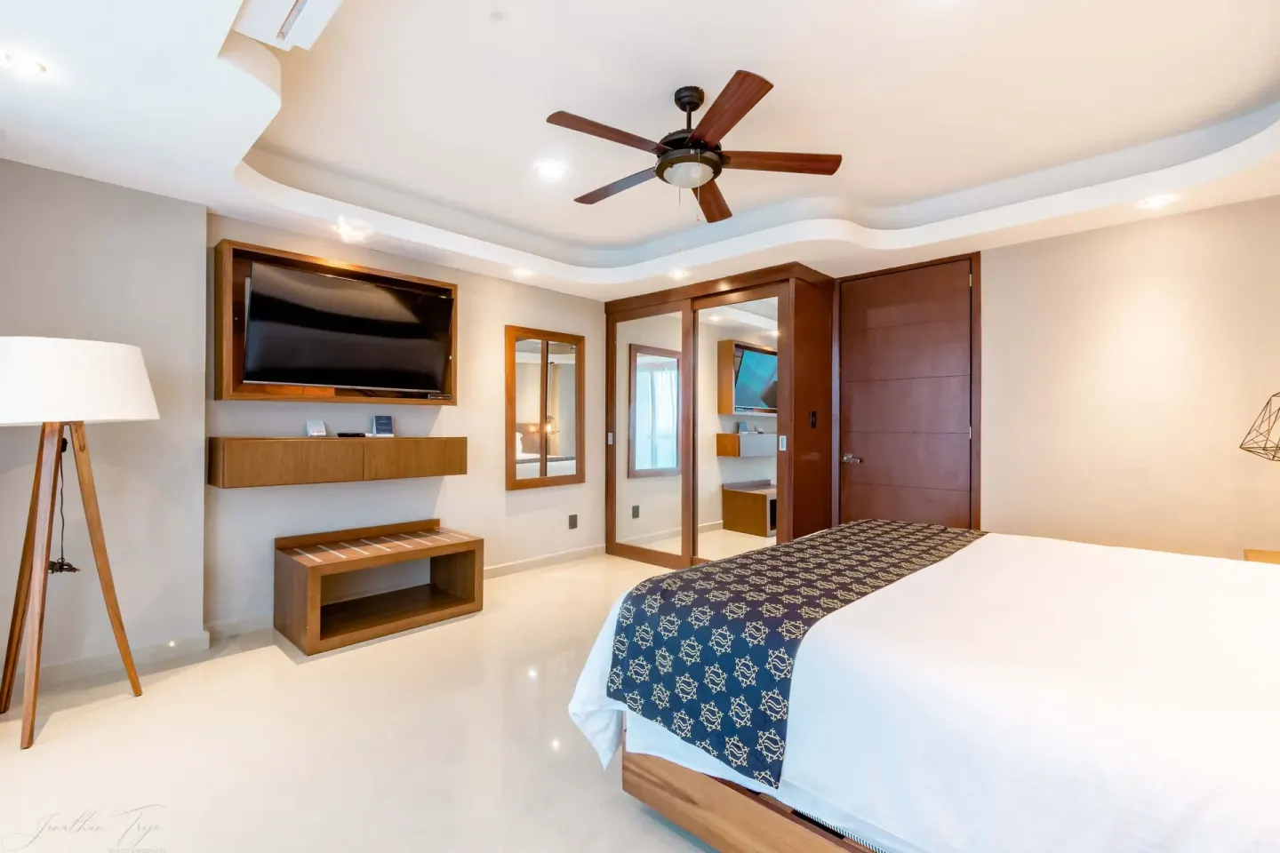 Guest room with king bed, TV, mirror closet, and ceiling fan at Ocean Dream Cancun.