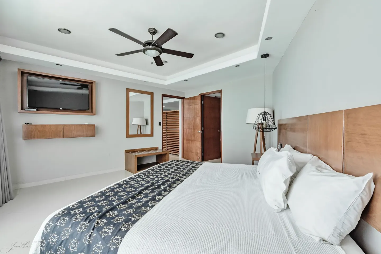 Guest room with king bed, wood headboard, TV, mirror, and entry door at Ocean Dream Cancun.