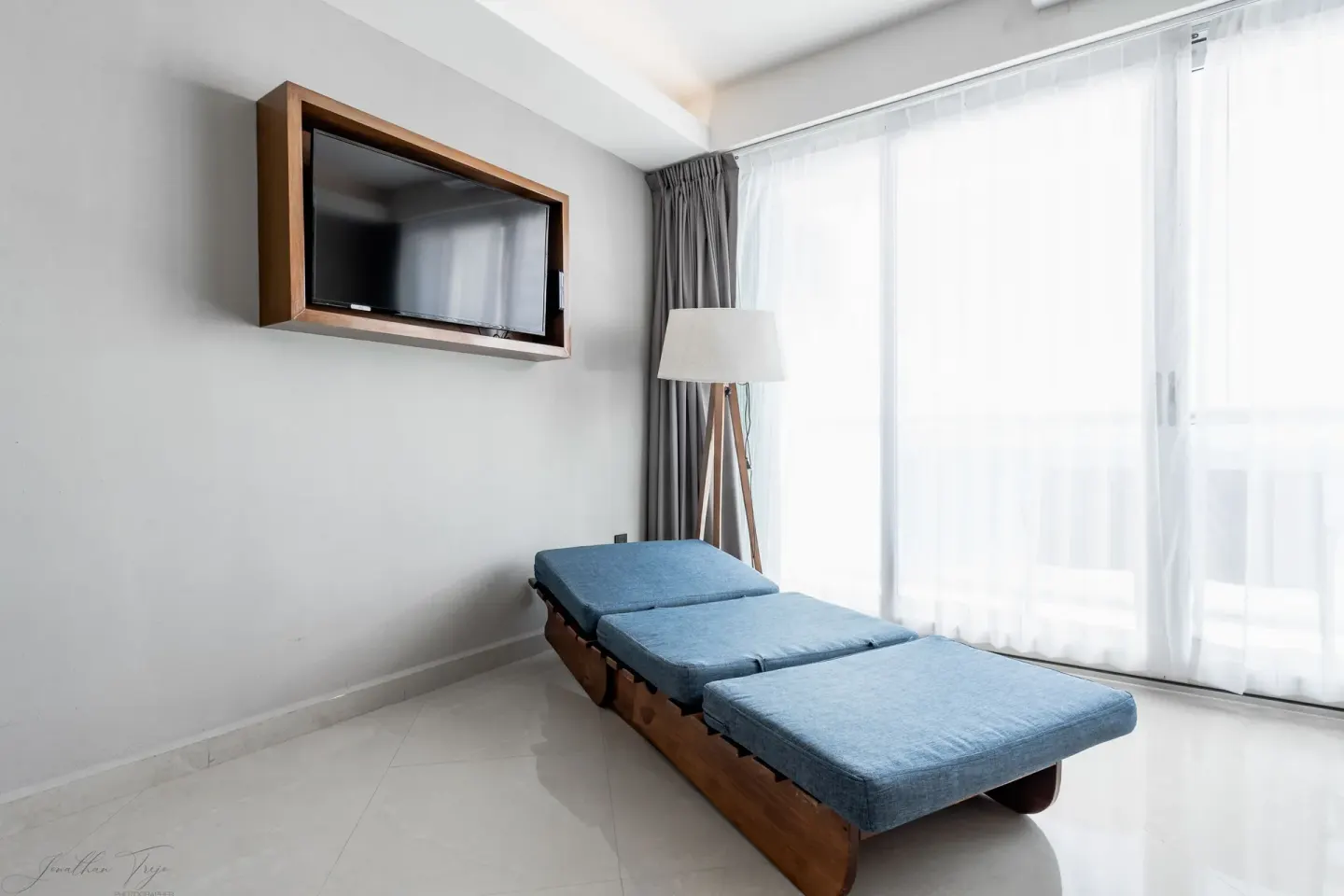 Guest room sitting area with blue chaise, wall TV, and balcony curtains at Ocean Dream Cancun.