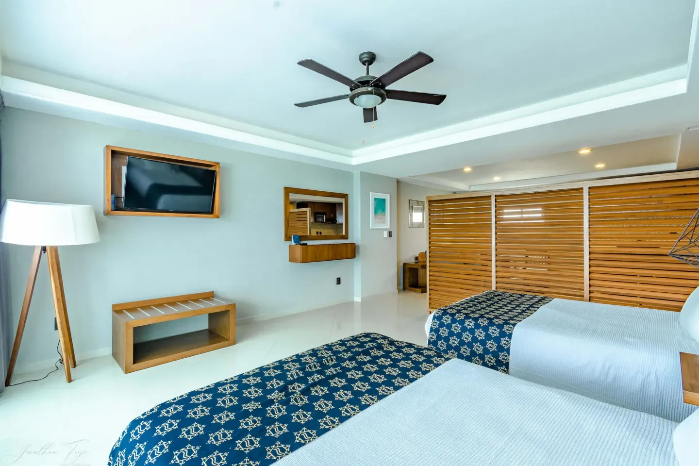 Guest room with two beds, wall TV, floor lamp, and wood shutters at Ocean Dream Cancun.