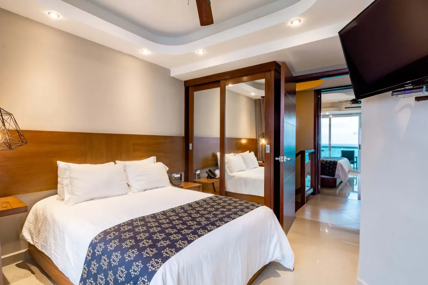 King guest room with mirrored closet and ocean-view doorway at Ocean Dream Cancun.