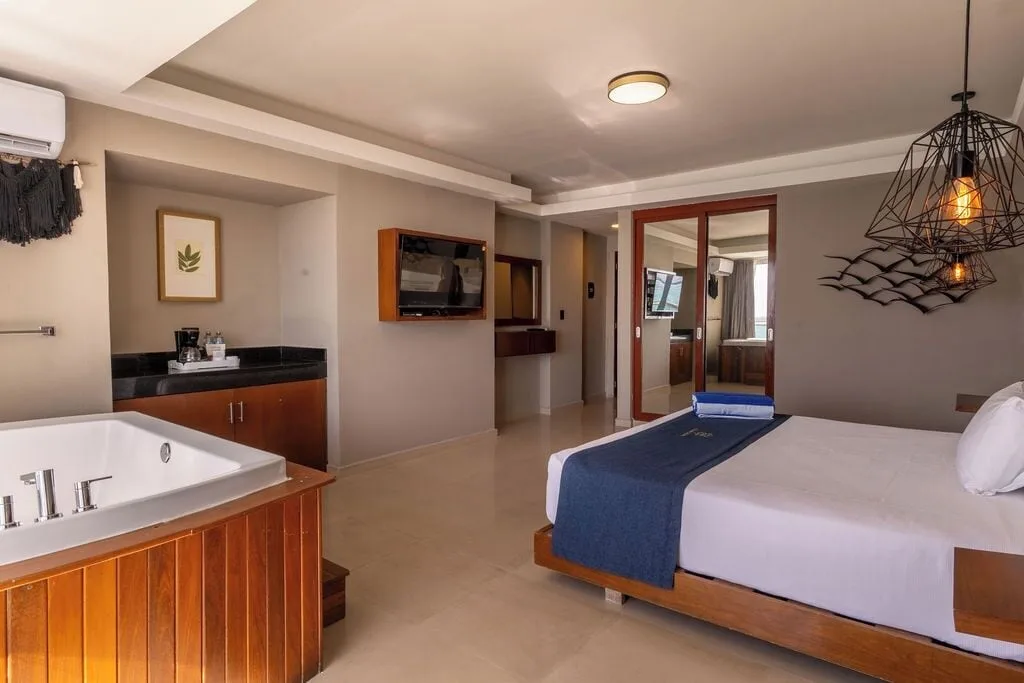 Deluxe room with king bed, tub, TV, and refreshment counter at Ocean Dream Cancun.