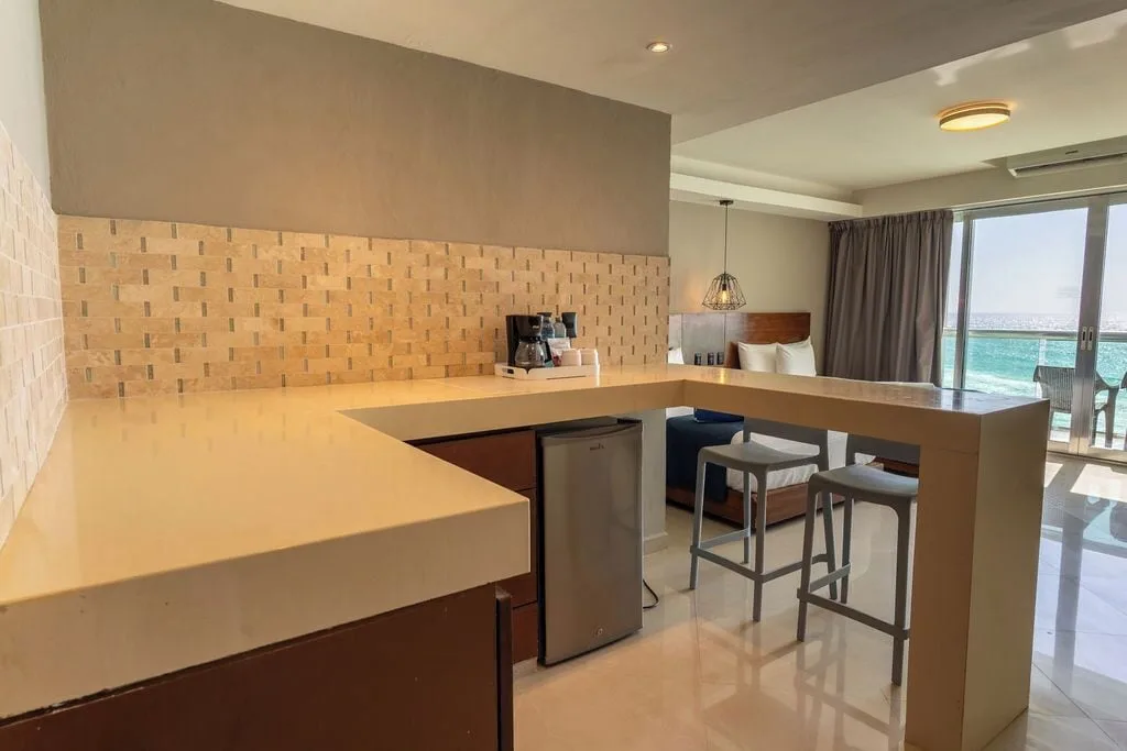 Deluxe room kitchenette with breakfast bar and ocean view beyond at Ocean Dream Cancun.