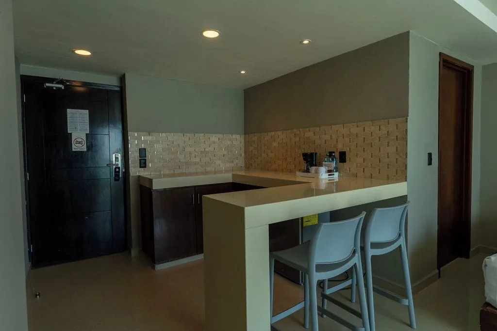Deluxe room kitchenette with bar stools near the entry door at Ocean Dream Cancun.