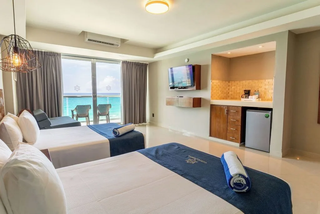 Deluxe room with two beds, kitchenette, TV, and ocean balcony at Ocean Dream Cancun.