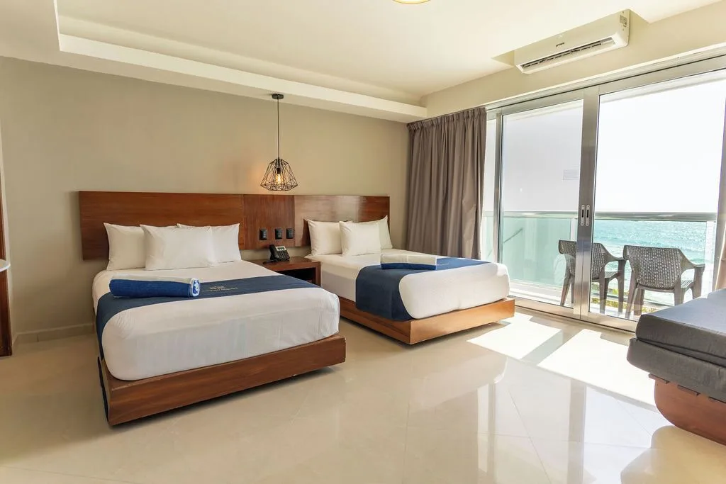 Deluxe room with two beds beside a bright ocean balcony at Ocean Dream Cancun.