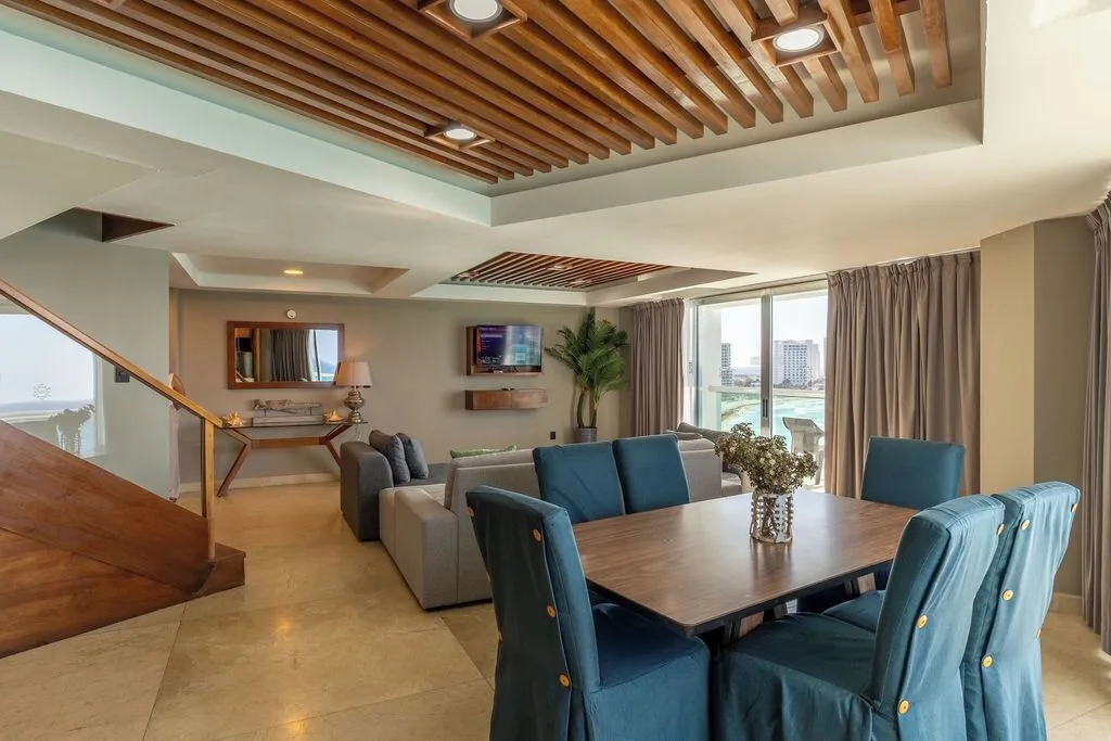 Diamond Suite dining and living area with blue chairs and balcony windows at Ocean Dream Cancun.