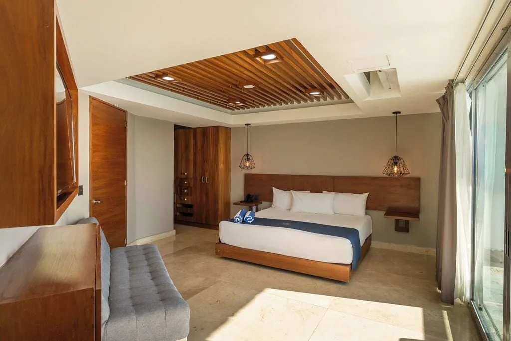 Diamond Suite king bedroom with sofa, wardrobe, and balcony doors at Ocean Dream Cancun.