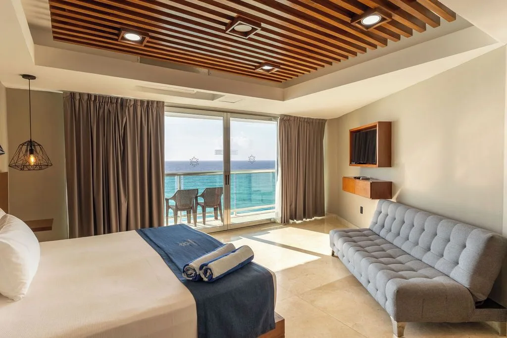 Diamond Suite bedroom with king bed, sofa, wall TV, and ocean balcony at Ocean Dream Cancun.