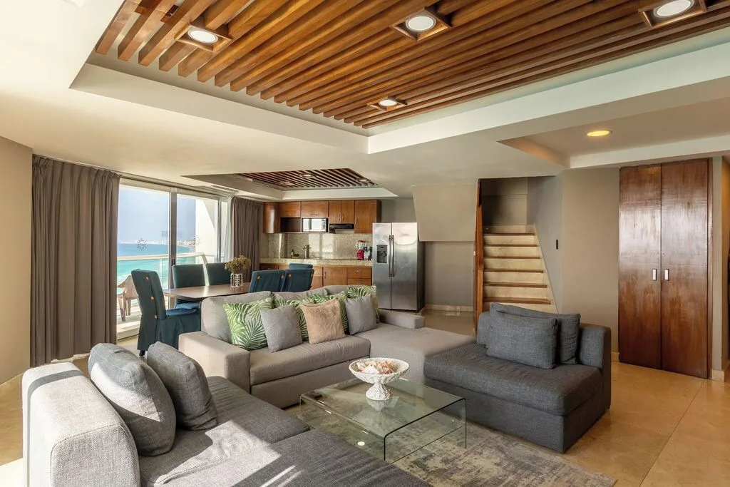 Diamond Suite living area with sofa, kitchen, dining table, and staircase at Ocean Dream Cancun.