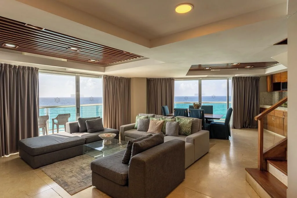 Diamond Suite living room with sofas, dining table, balcony, and ocean view at Ocean Dream Cancun.