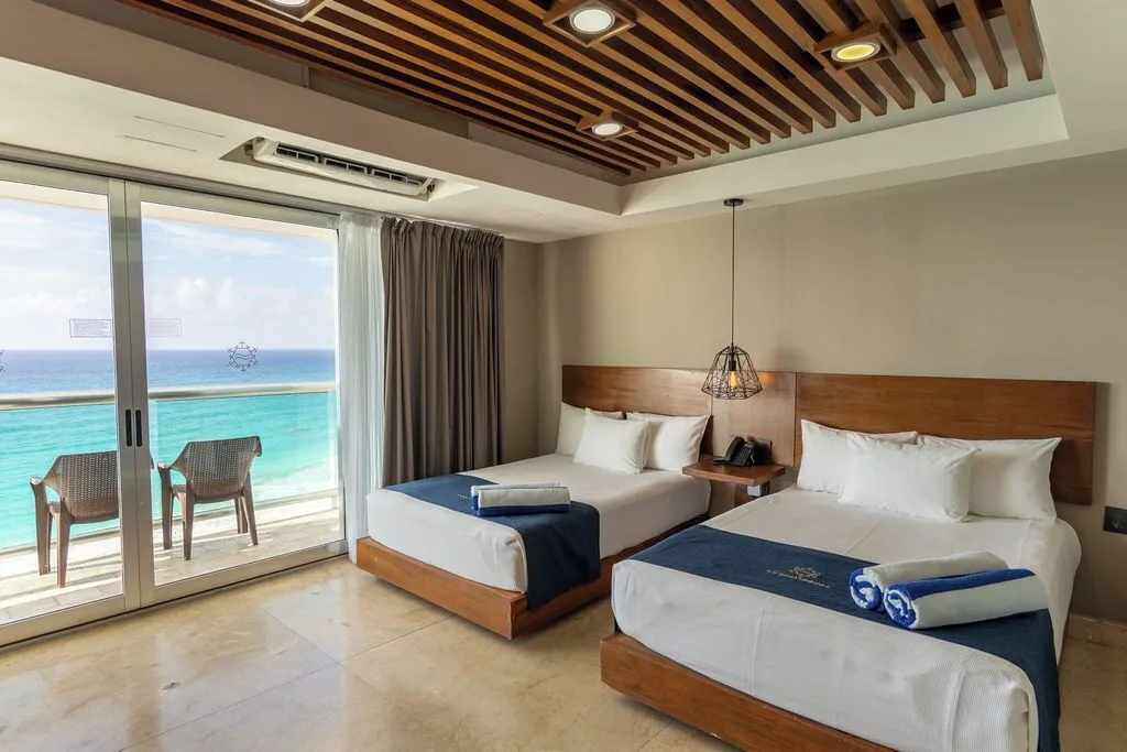 Diamond Suite two-bed bedroom with balcony seating and ocean view at Ocean Dream Cancun.