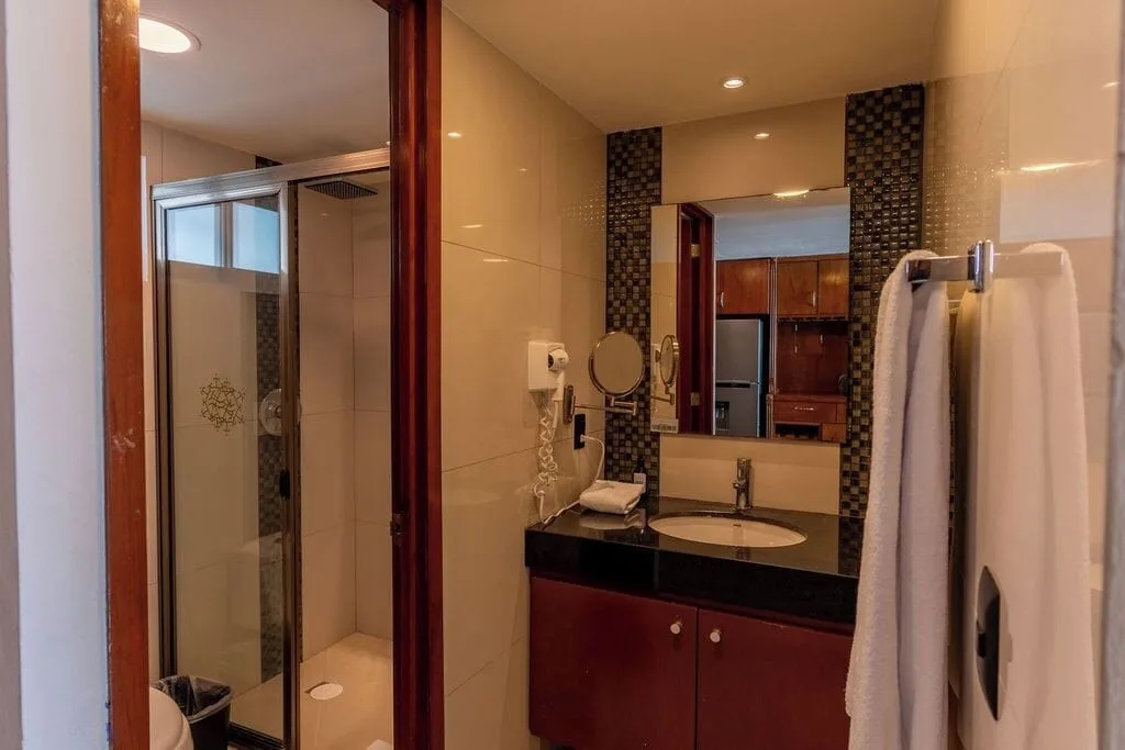 Penthouse bathroom with black vanity and glass shower at Ocean Dream Cancun.