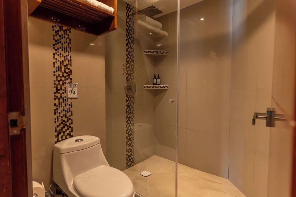 Penthouse bathroom with glass shower and toilet at Ocean Dream Cancun.