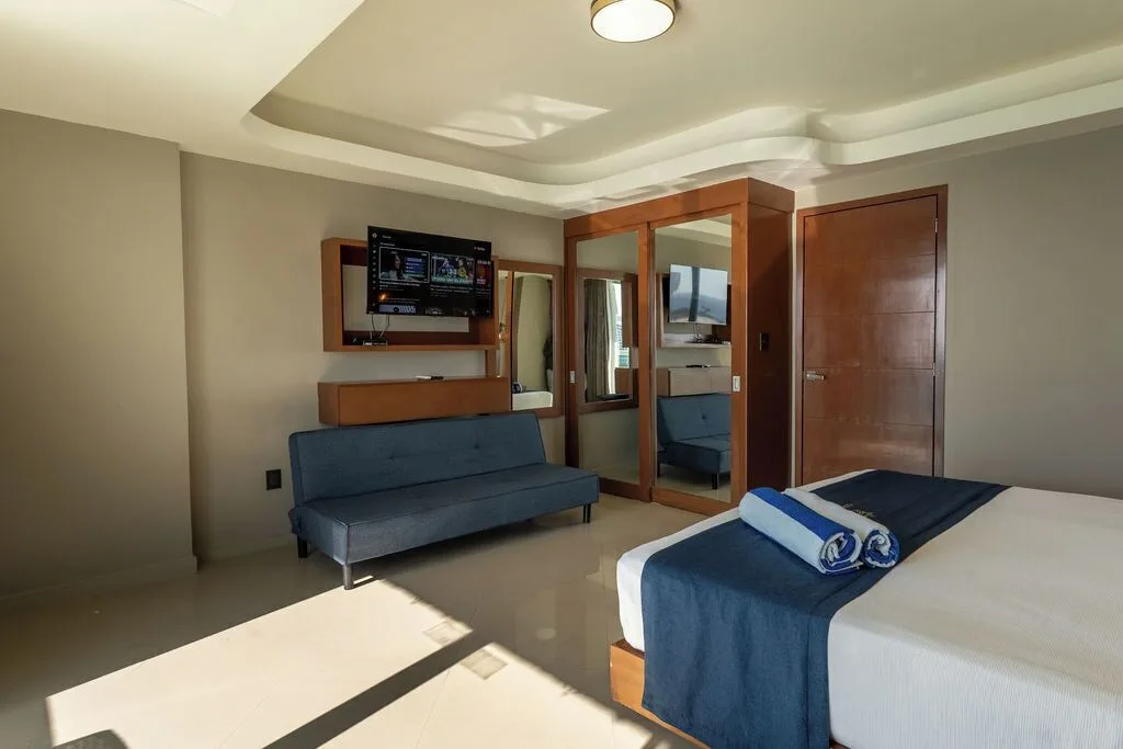 Penthouse bedroom with bed, sofa, TV and mirrored closet at Ocean Dream Cancun.