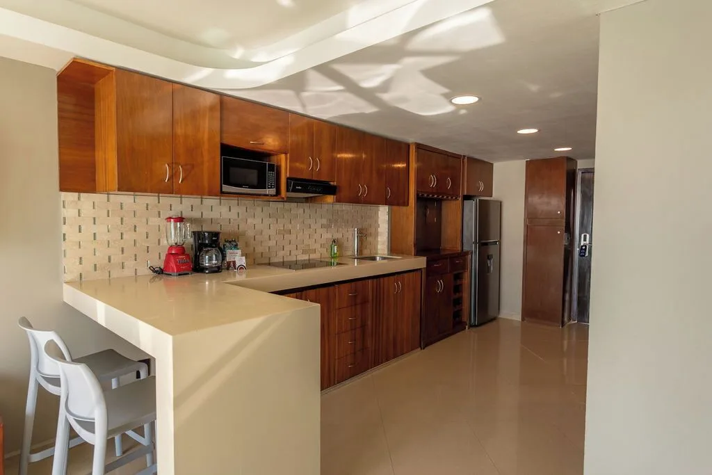 Penthouse kitchenette with wood cabinets and breakfast bar at Ocean Dream Cancun.