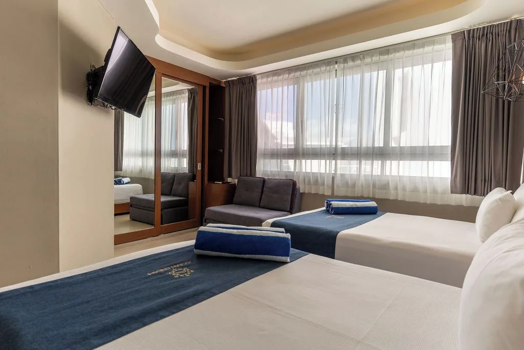 Two-bed penthouse bedroom with TV and sofa at Ocean Dream Cancun.