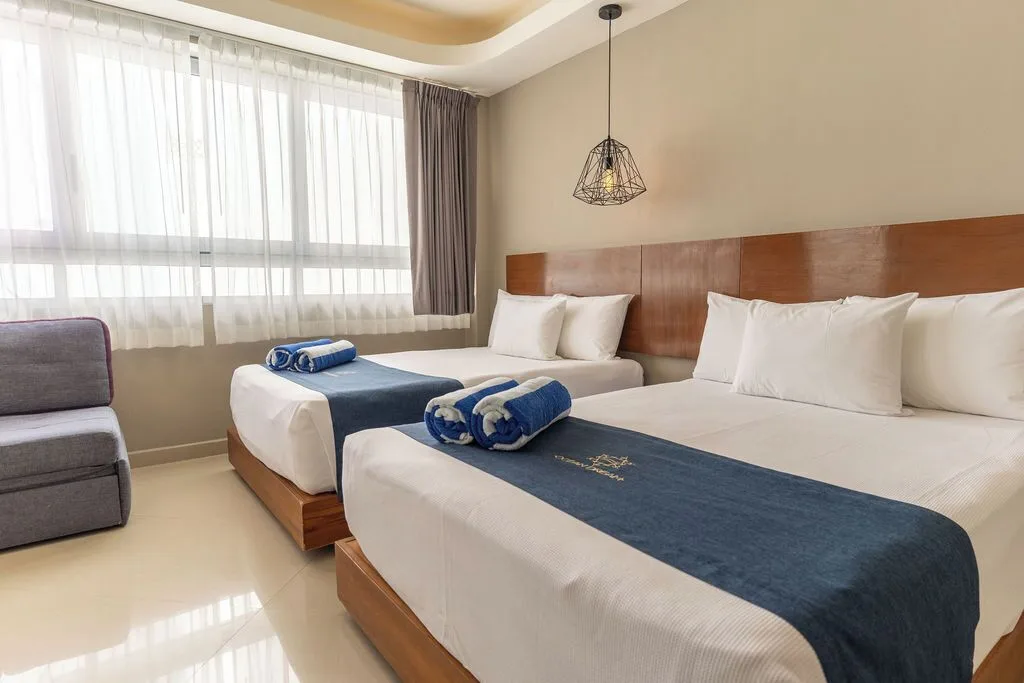 Two-bed penthouse bedroom with gray chair and window at Ocean Dream Cancun.