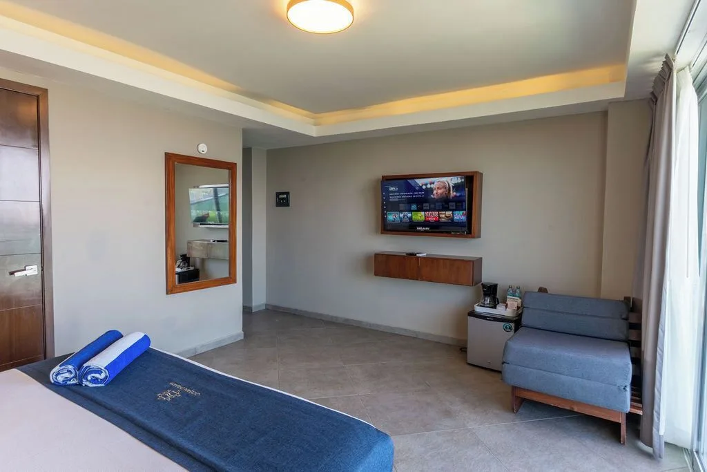Standard Room with king bed, TV, mirror and sofa at Ocean Dream Cancun.