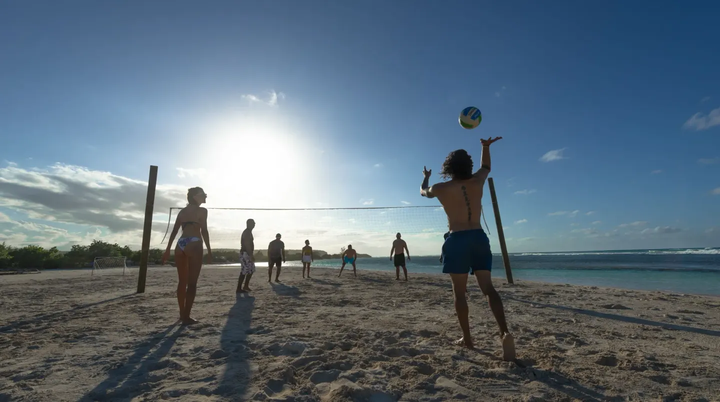 Guests play beach volleyball on the sand near the ocean at Ocean Eden Bay.