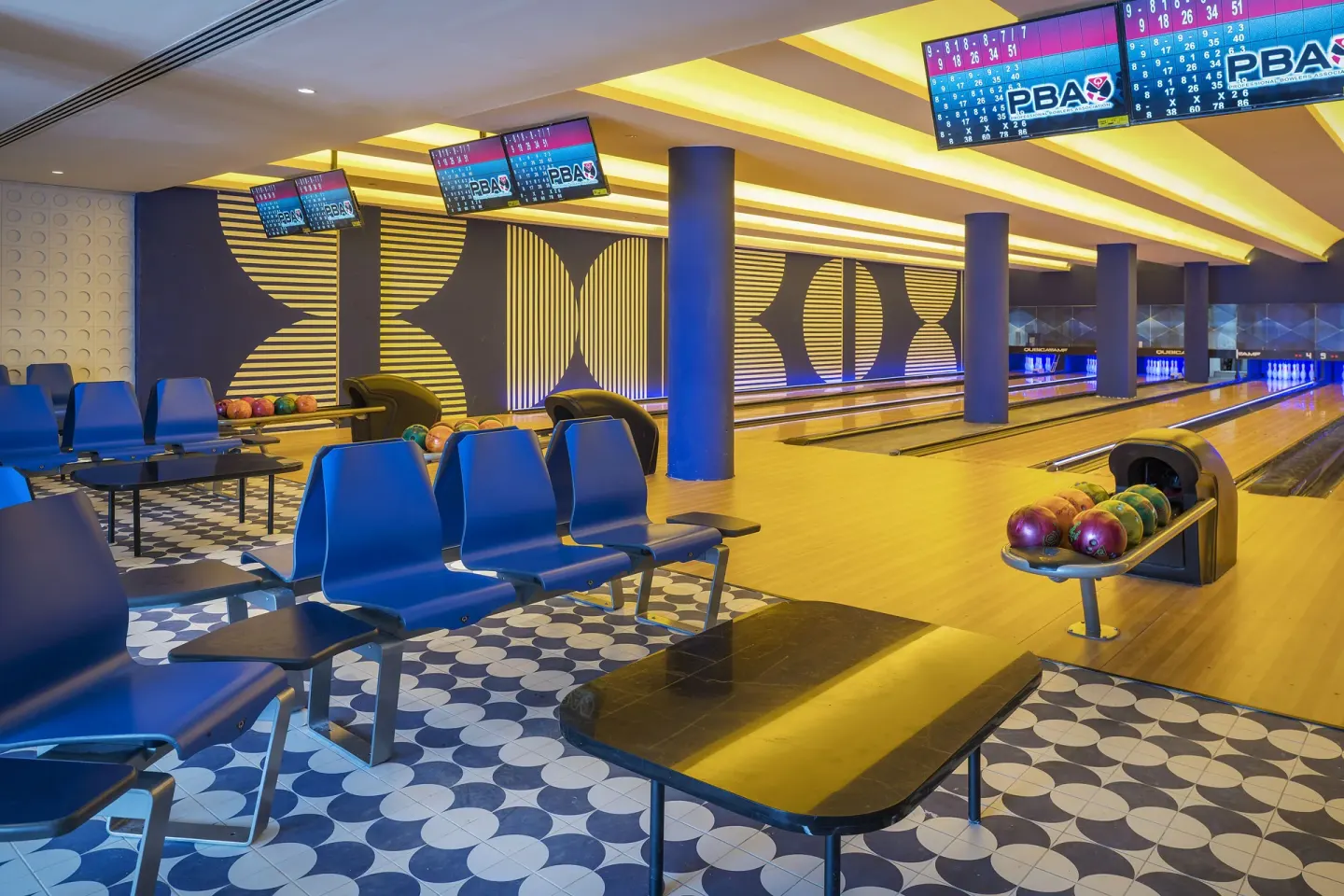 Bowling alley with ball racks, blue seats, and multiple lanes at Ocean Eden Bay.