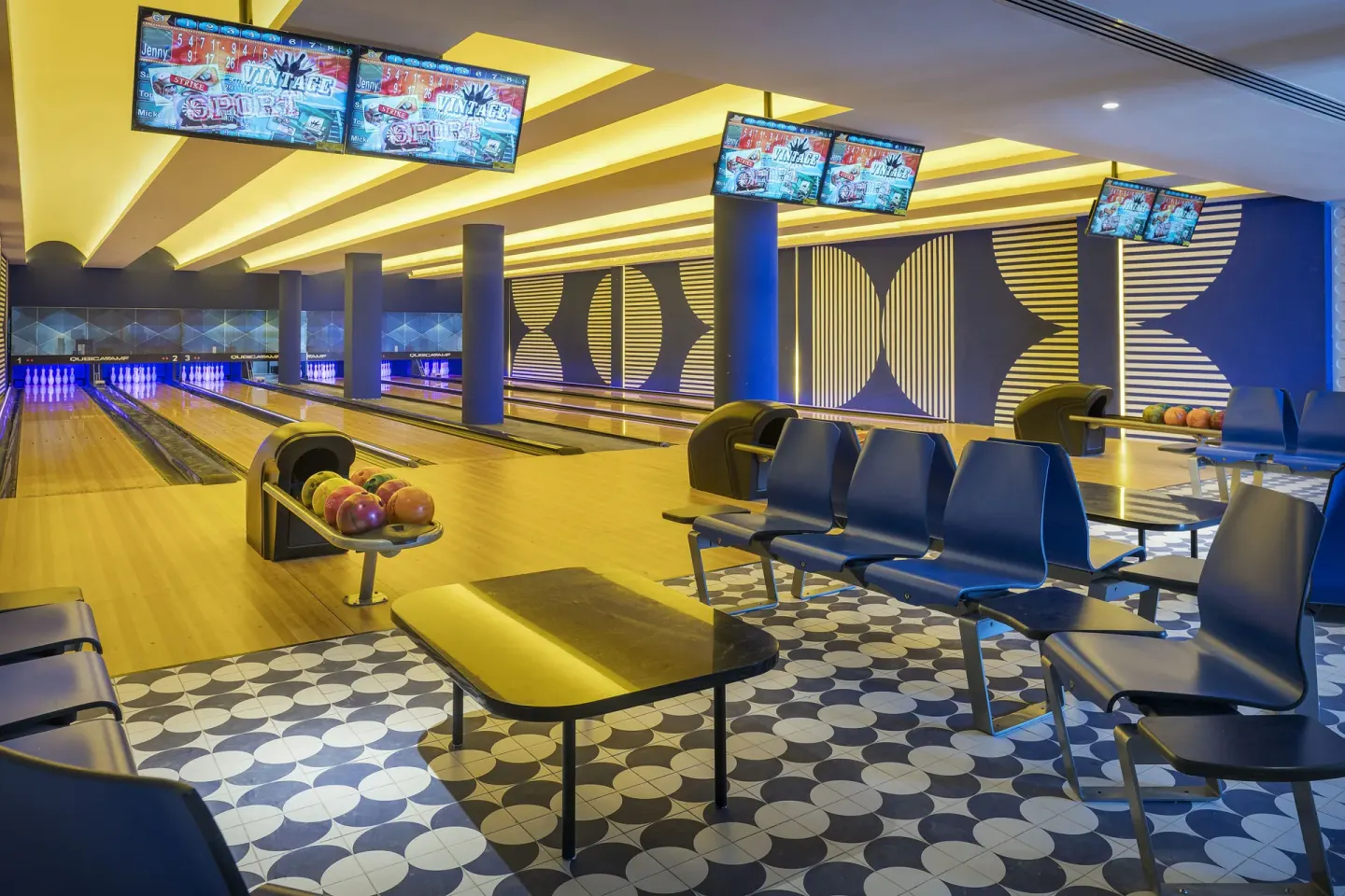 Bowling lanes with blue seating and overhead screens at Ocean Eden Bay.
