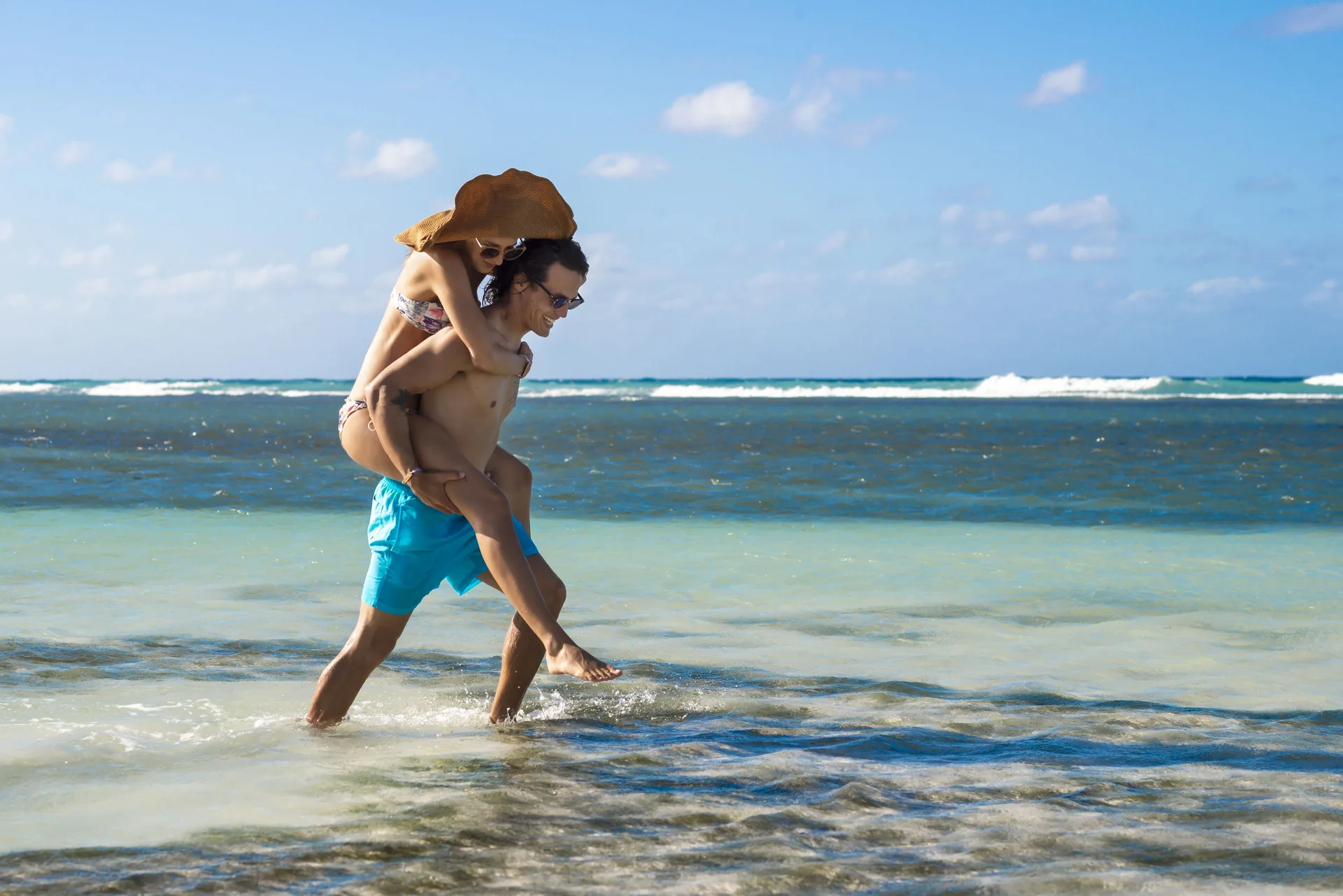 A couple walks through shallow sea water on the beach at Ocean Eden Bay.
