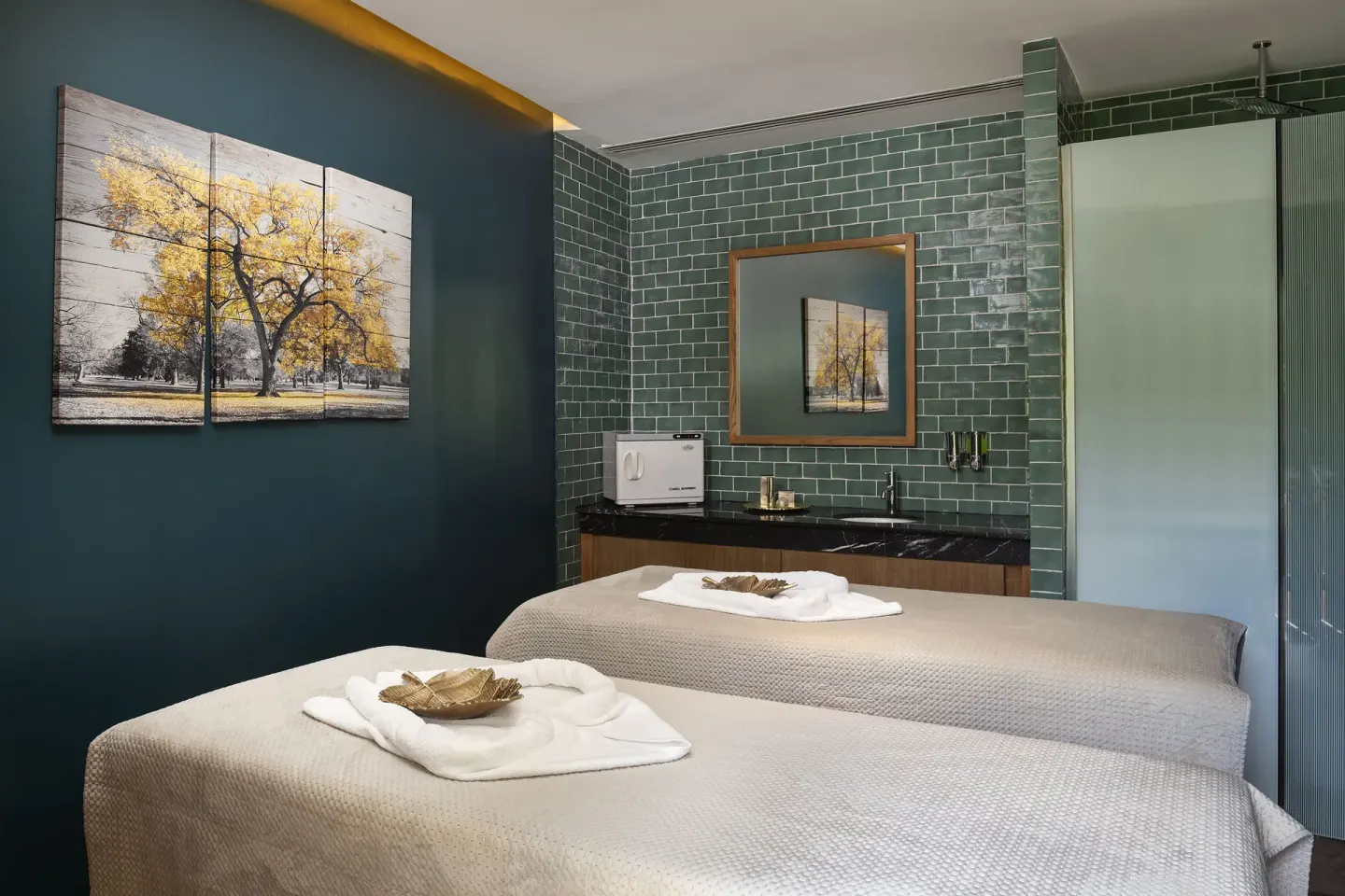 Spa treatment room with two massage beds and green tile walls at Ocean Eden Bay.
