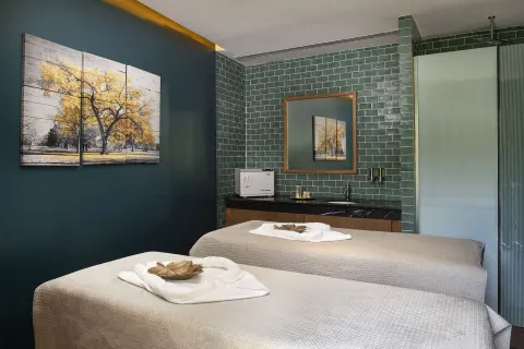 Spa treatment room with two massage beds and green tile walls at Ocean Eden Bay.