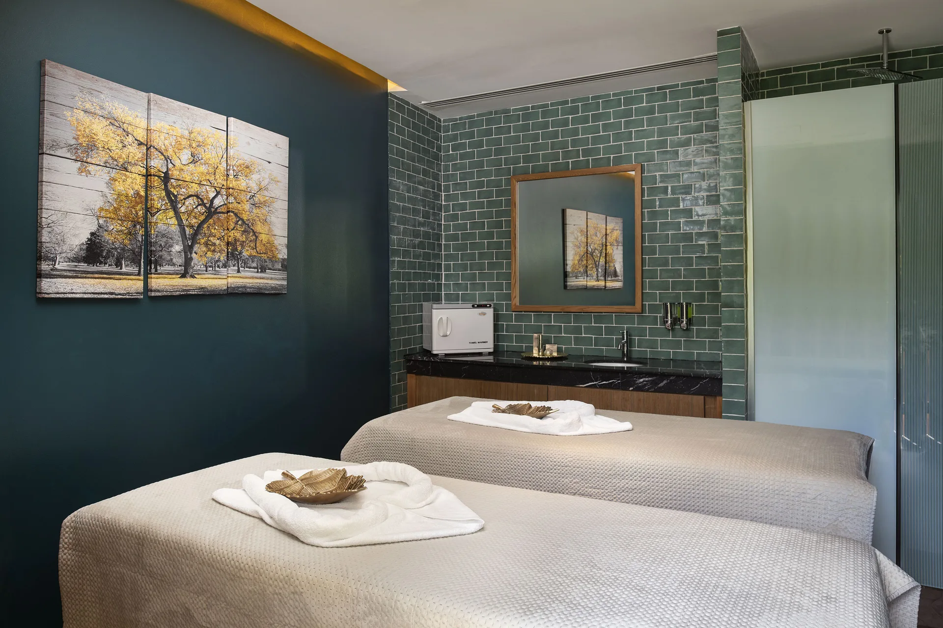 Spa treatment room with two massage beds and green tile walls at Ocean Eden Bay.