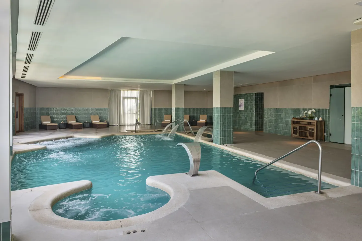 Indoor hydrotherapy pool with loungers and tiled columns at Ocean Eden Bay.