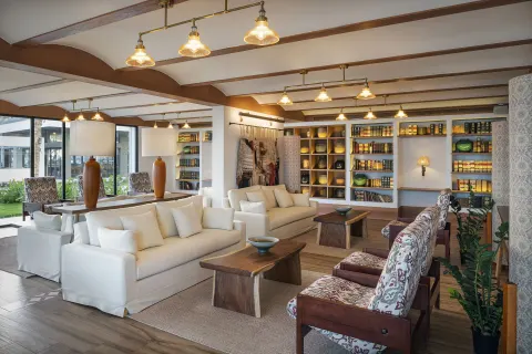 Resort lounge with white sofas, patterned chairs, and display shelves at Ocean Eden Bay.