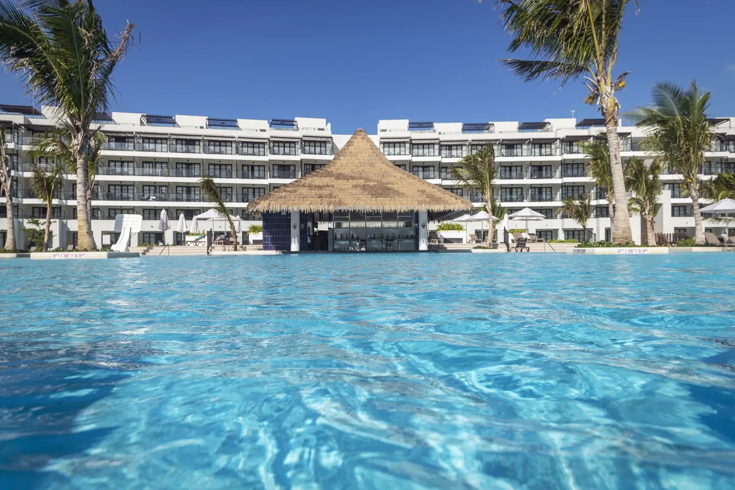 Main pool with thatched swim-up bar and resort buildings at Ocean Eden Bay.